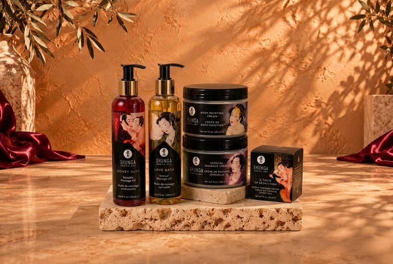 Shunga massage oil bottles, cream jars and boxed massage candle on travertine against a warm terracotta wall