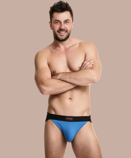 Burn – 008 Jock Blauw / Zwart S Pleasurements BURN 008 jockstrap in blauw en zwart gedragen door een model met gekruiste armen