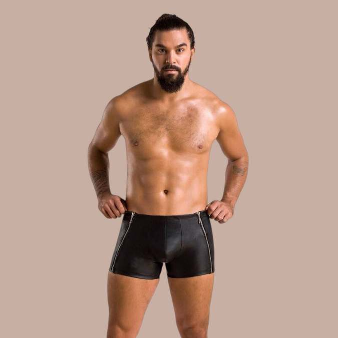 Model draagt Pleasurements Passion 049 shorts in matzwart met opvallende ritsdetails aan de zijkanten.
