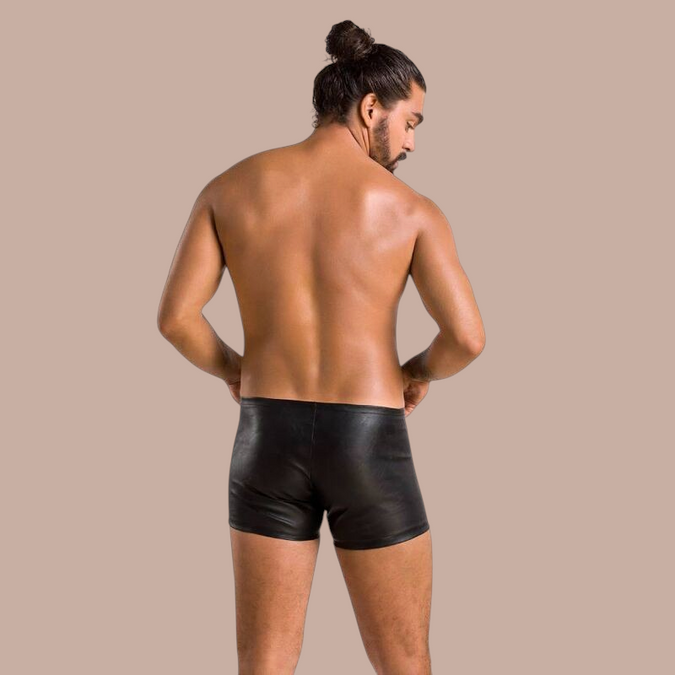 Man met knotje draagt Pleasurements Passion 049 shorts in mat zwart, gezien vanaf de achterkant.