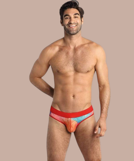 Anais Men – Falcon Slip S Pleasurements Anais Men Falcon slip met kleurrijk tie-dye patroon en rode tailleband gedragen door een model