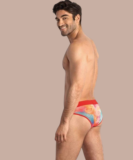 Anais Men – Falcon Slip S Pleasurements Anais Men Falcon slip met kleurrijk tie-dye patroon en rode tailleband gedragen door een model