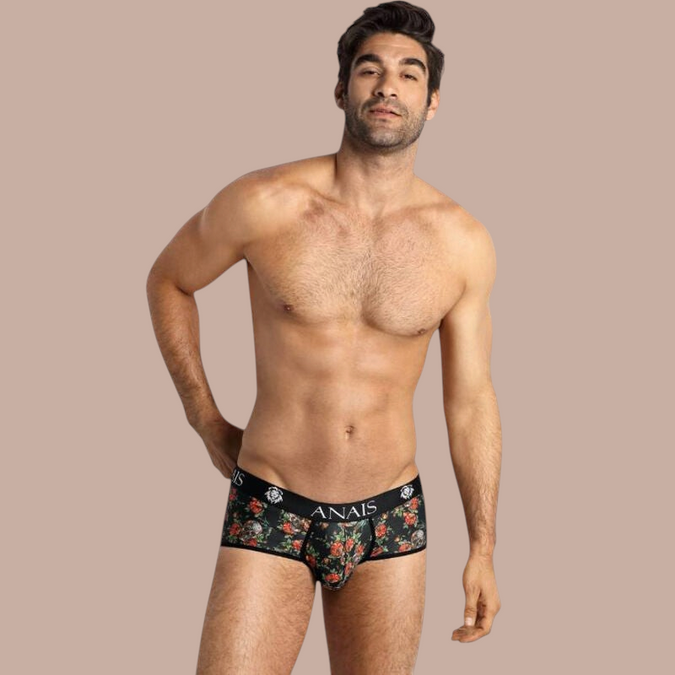 Model draagt Anais Men Power Brief met bloemenprint en Pleasurements merklogo op de zwarte tailleband.