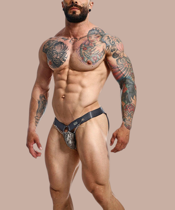 Pleasurements Mob Dngeon grijze leren jockstrap met metalen kettingdetails gedragen door een gespierd model.
