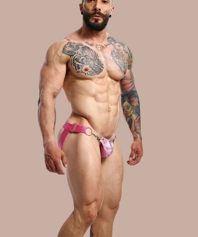 Pleasurements Mob Dngeon roze jockstrap met metalen ringen en lederen accenten gedragen door een getatoeëerd model