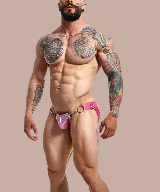 Pleasurements Mob Dngeon jockstrap in roze metaal en leer gedragen door een gespierd model met tatoeages