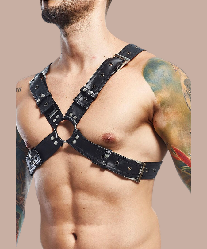 Pleasurements Mob Dngeon zwart lederen harnas met metalen gespen gedragen door een man met tatoeages