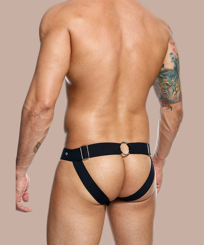 Pleasurements Mob Dngeon zwarte leren jockstrap met metalen ringen gedragen door een man op een witte achtergrond
