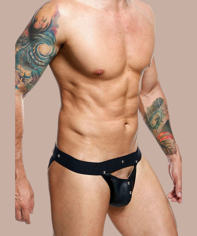 Pleasurements Mob Dngeon zwarte leren jockstrap met metalen studs gedragen door een man met tatoeages