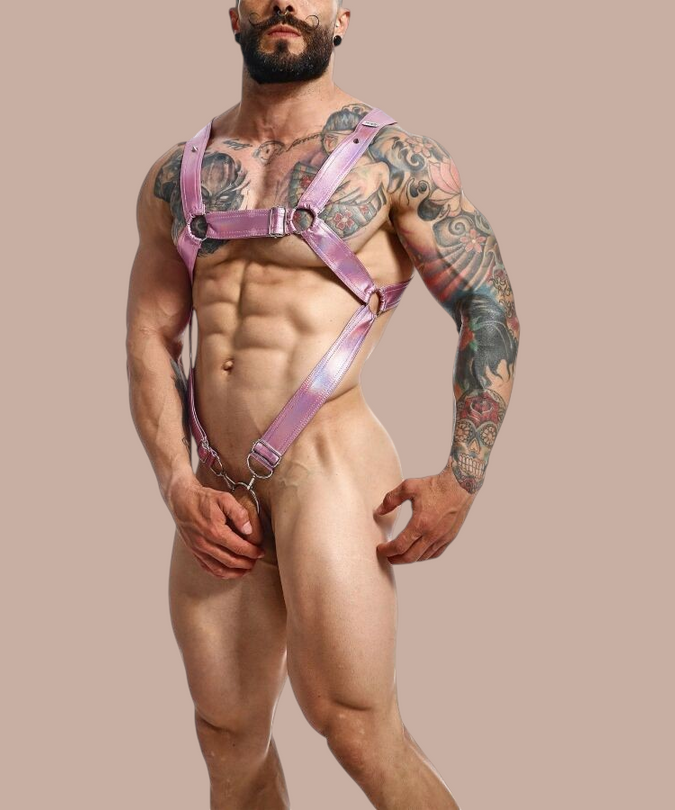Pleasurements Mob Dngeon roze metallic leren penis harnas met metalen ringen gedragen door een getatoeΓ«erde man