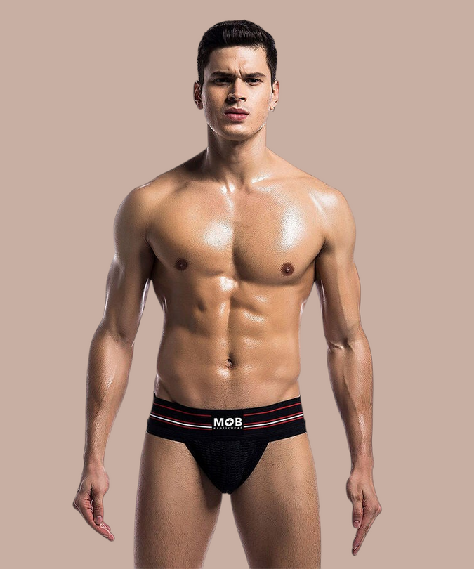 Pleasurements Mob klassieke zwarte string gedragen door een gespierd model met rode accenten op de tailleband