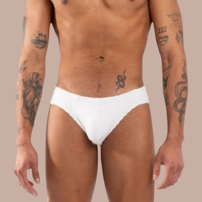 Pleasurements Burn 021 witte slip gedragen door een getatoeëerd model voor een verfijnde en sensuele uitstraling.