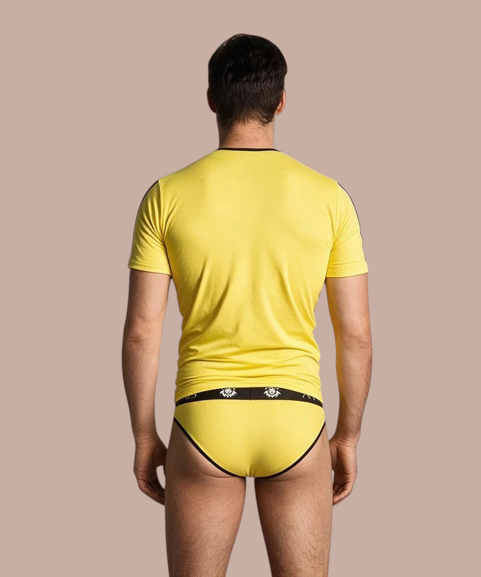 Pleasurements Anais Men Tokio T-shirt in geel met zwarte accenten, gedragen door een man op de rug gezien.