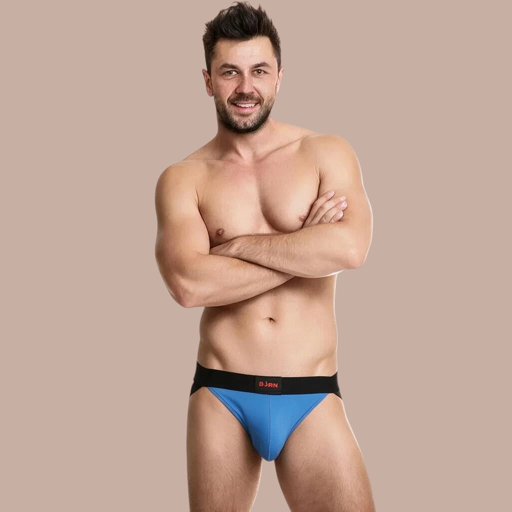 Pleasurements BURN 008 jockstrap in blauw en zwart gedragen door een model met gekruiste armen