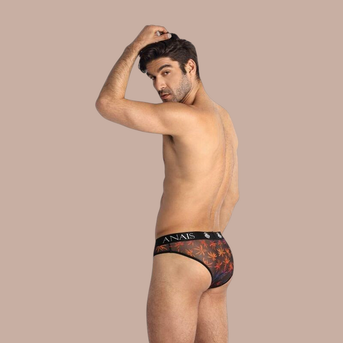 Pleasurements Anais Men Chill Slip met oranje palmbladprint op zwarte doorschijnende stof gedragen door een model