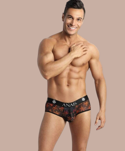 Pleasurements Anais Men Chill Jock Bikini met palmboomprint en zwarte tailleband gedragen door een lachend model
