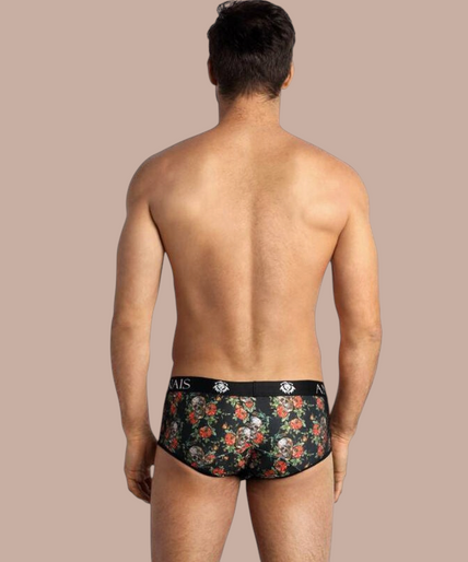 Model draagt Anais Men Power Brief met bloemenprint en Pleasurements merklogo op de zwarte tailleband.