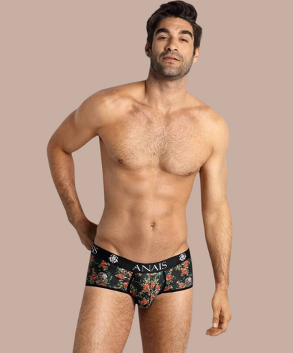 Model draagt Anais Men Power Brief met bloemenprint en Pleasurements merklogo op de zwarte tailleband.