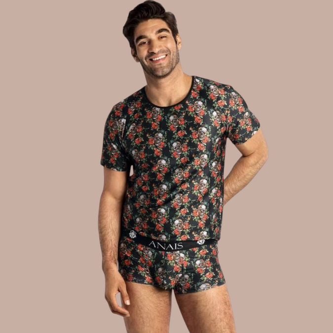 Pleasurements Anais Men Power T-shirt met zwart, rood en wit schedel- en rozenpatroon gedragen door een lachend model