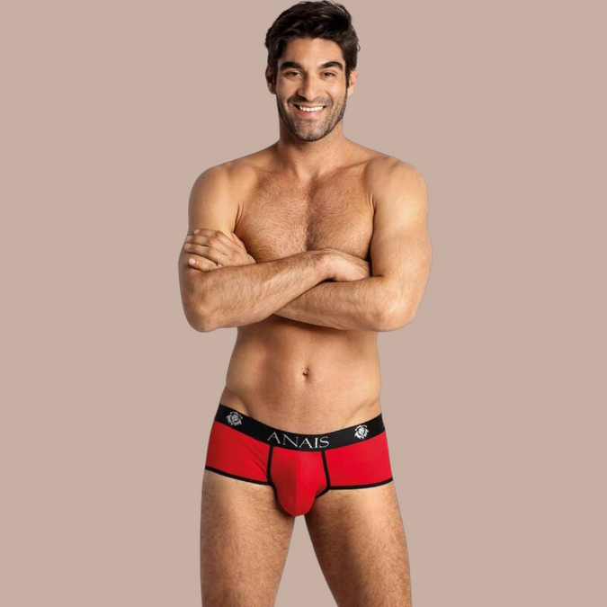 Pleasurements Anais Men Soul Brief in rood met zwarte tailleband en logo, gedragen door een glimlachend model.