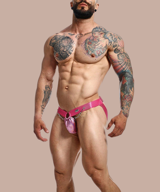 Pleasurements Mob Dngeon jockstrap in roze leer en metaal gedragen door een gespierd model met tatoeages