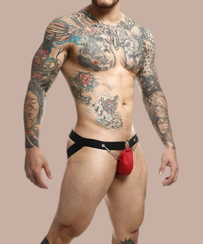Pleasurements Mob Dngeon rode jockstrap met metalen kettingen gedragen door een getatoeëerde man