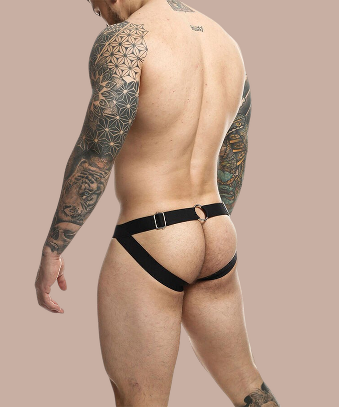 Pleasurements Mob Dngeon gele jockstrap met metalen ring en kettingdetails gedragen door een getatoeëerde man