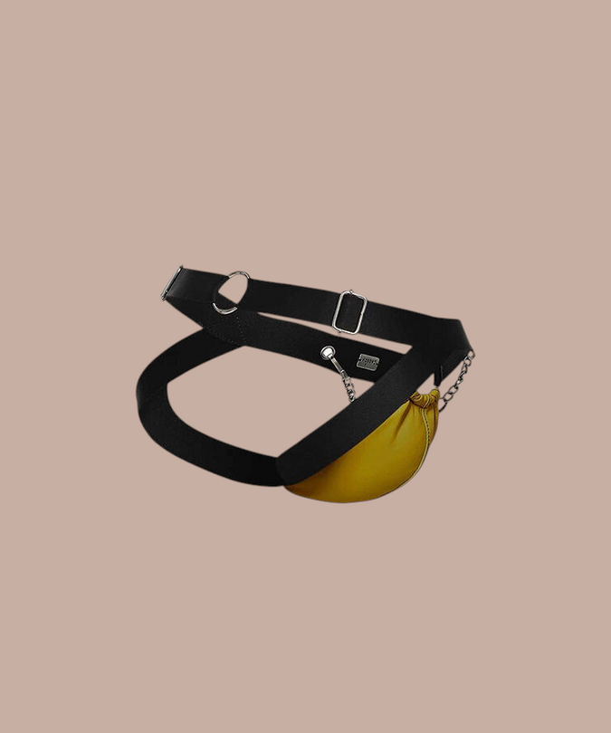 Pleasurements Mob Dngeon gele jockstrap met zwarte banden, metalen kettingen en lederen accenten voor een sensuele look.