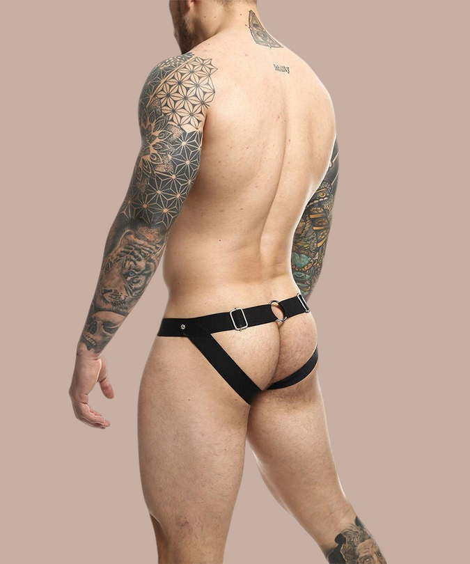 Pleasurements Mob Dngeon jockstrap in zwart leer en metaal gedragen door een getatoeëerde man van achteren gezien