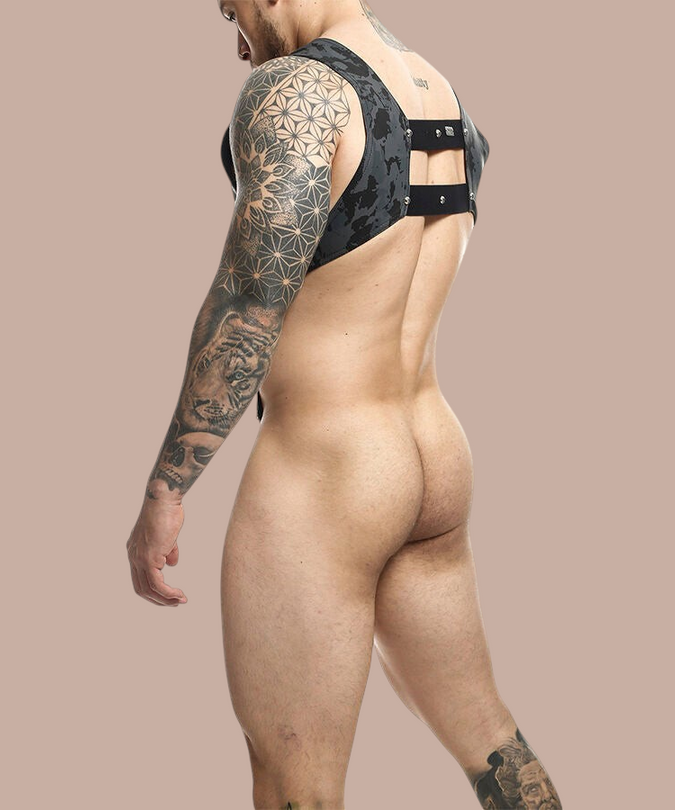 Pleasurements Mob Dngeon harnas van leer en metaal met zilveren penisring gedragen door een getatoeëerde man