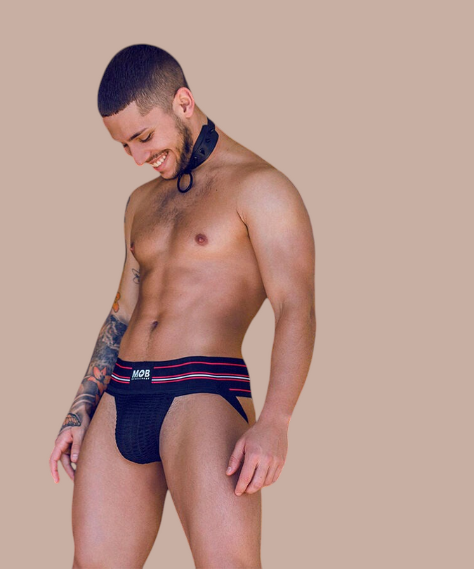Pleasurements Mob zwarte string met sportieve tailleband gedragen door een man in een stedelijke omgeving