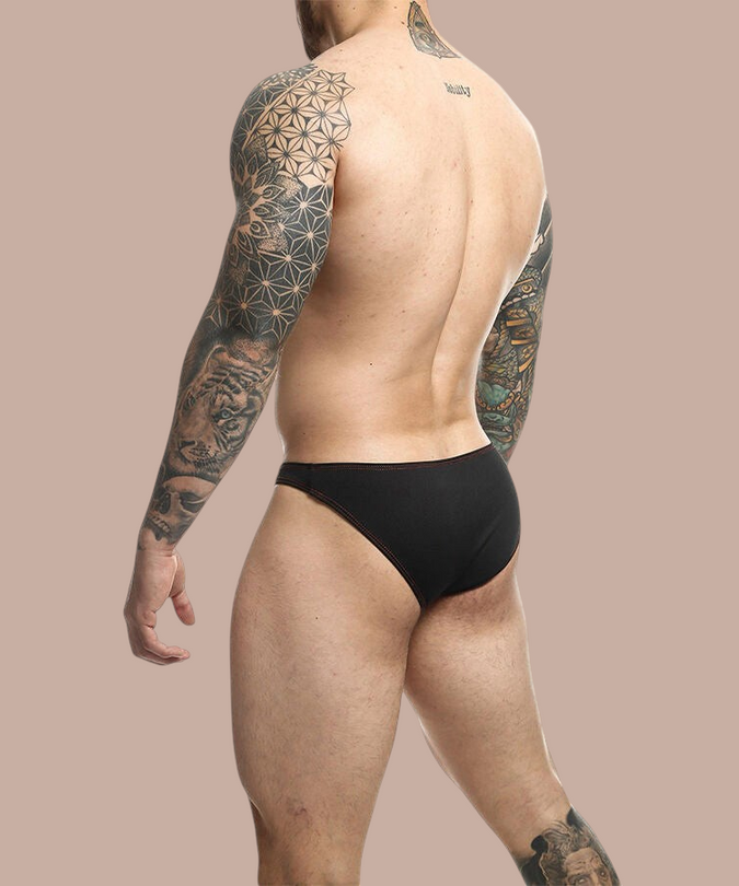 Pleasurements Mob zwarte Toucan zwemslip gedragen door een getatoeëerde man, achterkant zicht