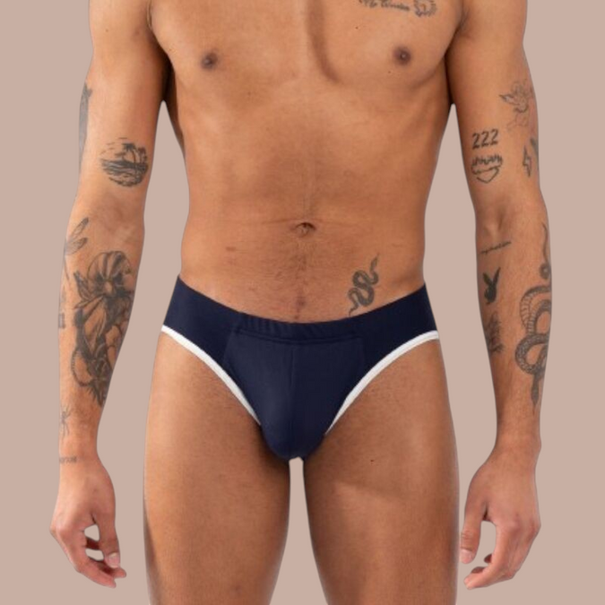 Pleasurements Burn 020 marineblauwe slip met witte bies gedragen door een getatoeëerd model