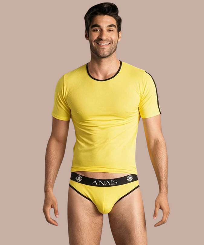 Pleasurements Anais Men Tokio T-shirt in geel met zwarte accenten gedragen door een glimlachend model